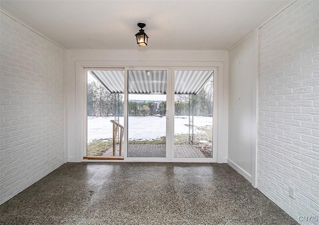 interior space featuring ornamental molding, brick wall, and speckled floor