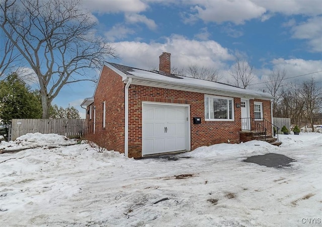 view of front of property featuring a garage, brick siding, a chimney, and fence