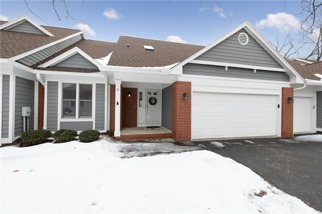 view of front of home with brick siding, roof with shingles, and an attached garage