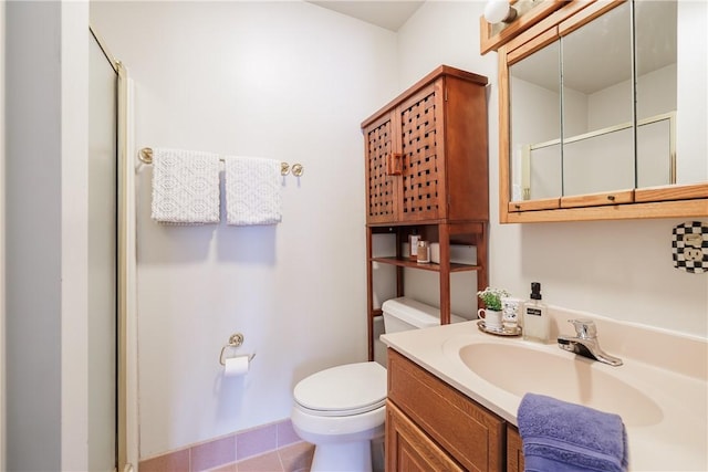 bathroom with a shower with shower door, vanity, toilet, and tile patterned floors