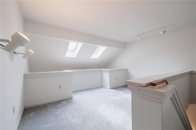 additional living space with light carpet, lofted ceiling with skylight, and baseboards