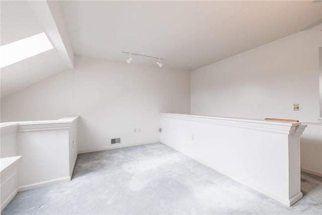 additional living space featuring light colored carpet, visible vents, and vaulted ceiling with skylight