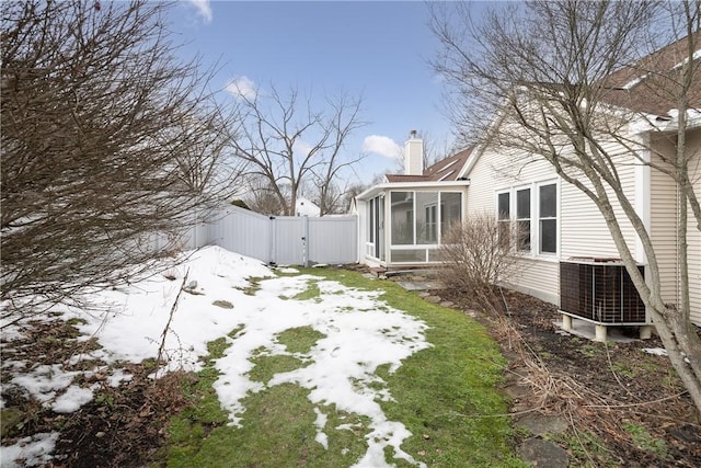 view of yard with a sunroom, fence, central AC unit, and a gate