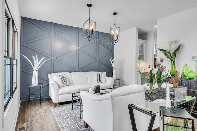 living room featuring visible vents, a decorative wall, an accent wall, wood finished floors, and a chandelier