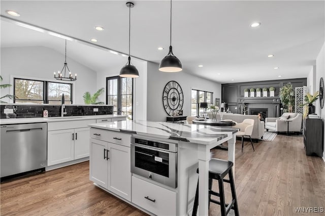 kitchen with a warm lit fireplace, plenty of natural light, appliances with stainless steel finishes, and a sink