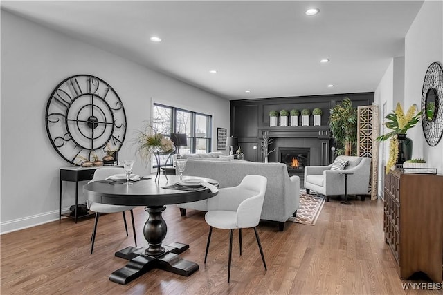 interior space with recessed lighting, baseboards, wood finished floors, and a glass covered fireplace