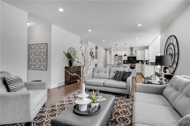 living area featuring recessed lighting, visible vents, light wood-style flooring, and baseboards