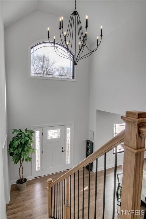 entryway with stairs, high vaulted ceiling, baseboards, and wood finished floors