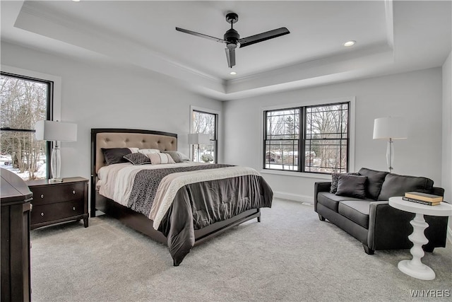 carpeted bedroom featuring multiple windows, a raised ceiling, and baseboards