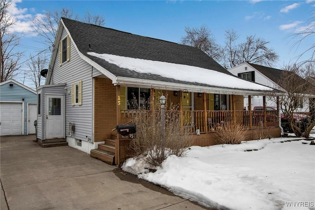 view of front of home featuring entry steps, a shingled roof, an outbuilding, covered porch, and brick siding