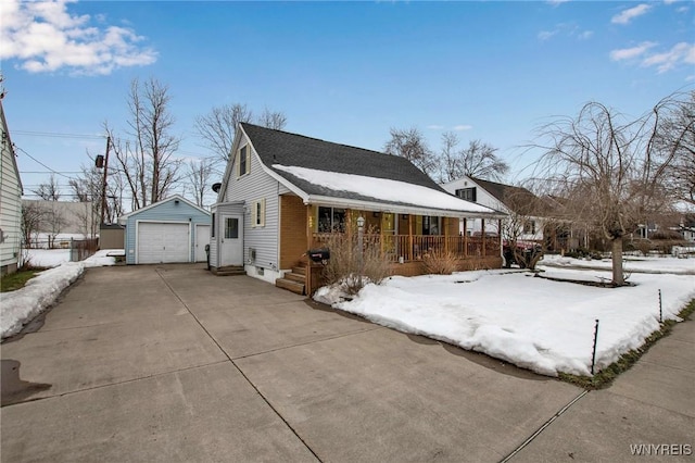 snow covered property with a detached garage, covered porch, entry steps, an outdoor structure, and driveway