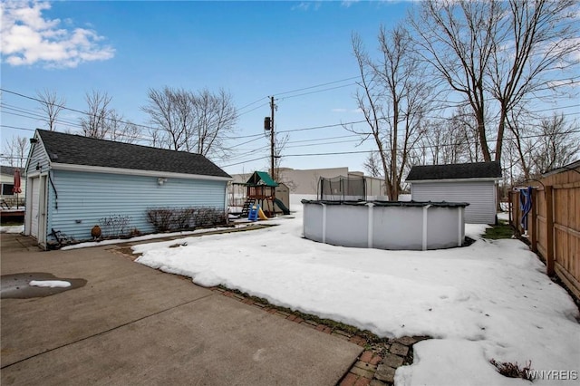 view of yard with a covered pool, fence, a playground, and an outdoor structure