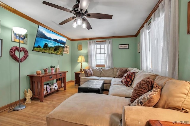 living room featuring light wood-style floors, baseboards, a ceiling fan, and crown molding