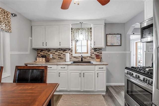 kitchen with appliances with stainless steel finishes, a sink, white cabinetry, and decorative backsplash