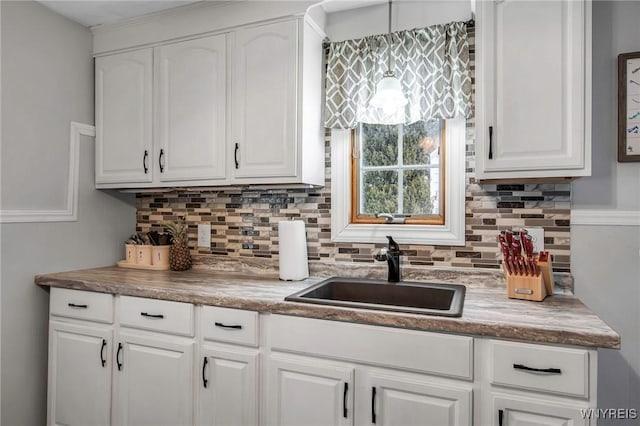 kitchen with tasteful backsplash, white cabinets, and a sink