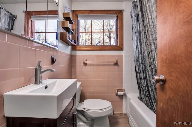 full bath with shower / tub combo, vanity, toilet, and tile walls