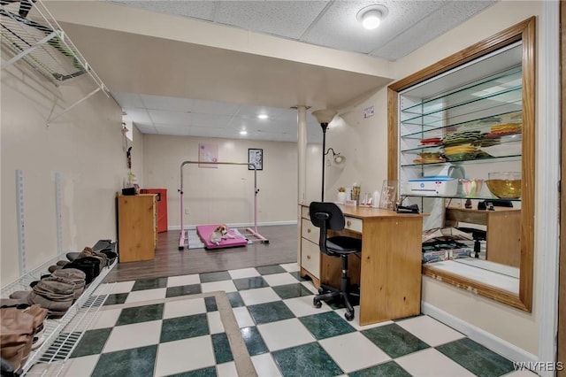 interior space with baseboards, a paneled ceiling, and tile patterned floors