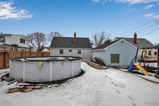 snow covered rear of property featuring a fenced in pool and fence