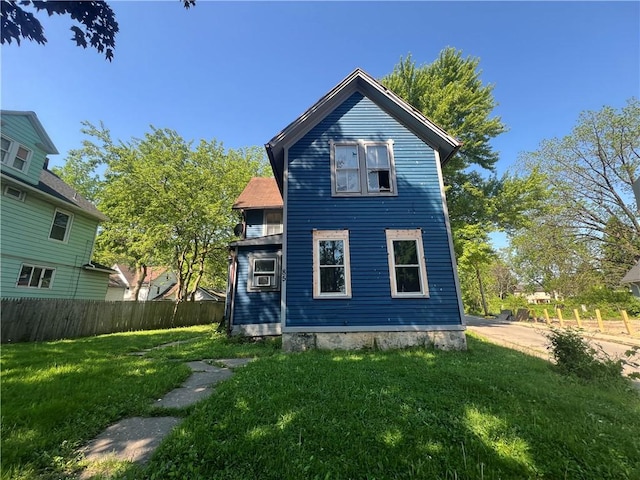 back of property with a lawn and fence