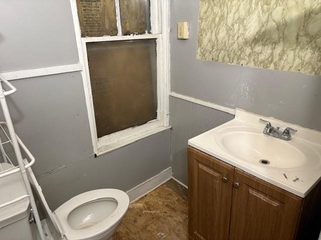 half bathroom featuring toilet, wainscoting, and vanity