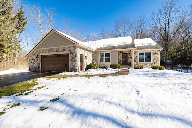 single story home featuring stone siding, aphalt driveway, an attached garage, and fence