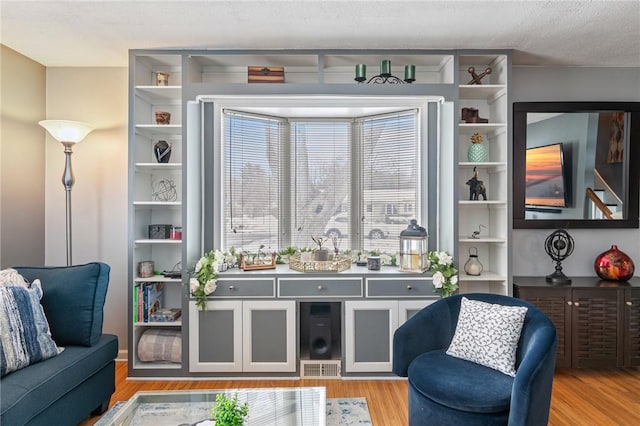 living area with light wood-type flooring, visible vents, and a textured ceiling