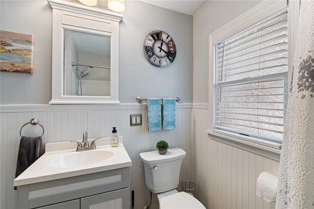 full bathroom featuring a wainscoted wall, a healthy amount of sunlight, vanity, and toilet