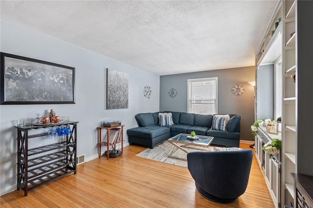 living room with a textured ceiling, baseboards, and wood finished floors