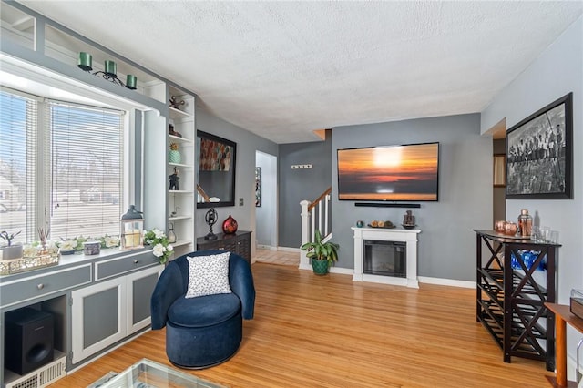 interior space featuring baseboards, a fireplace, a textured ceiling, and light wood finished floors