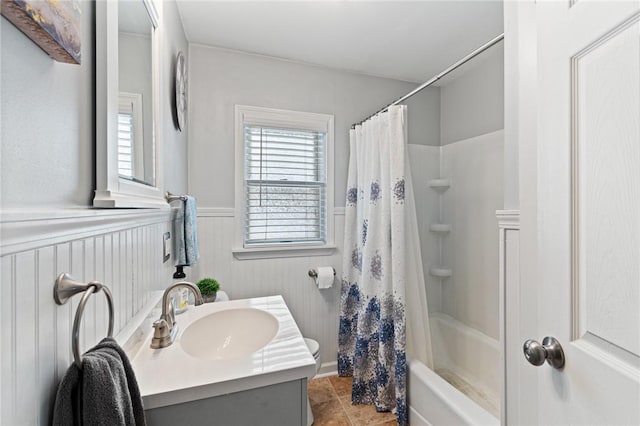 bathroom featuring a wainscoted wall, shower / tub combo, vanity, and a healthy amount of sunlight