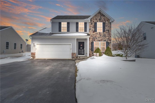 view of front of property featuring a garage, stone siding, and aphalt driveway