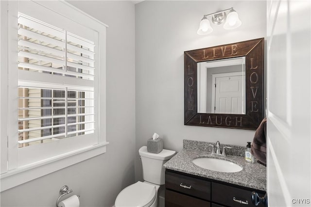 half bathroom with toilet, a wealth of natural light, and vanity