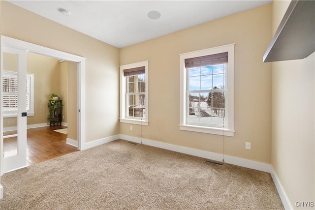 spare room with baseboards, visible vents, and carpet flooring