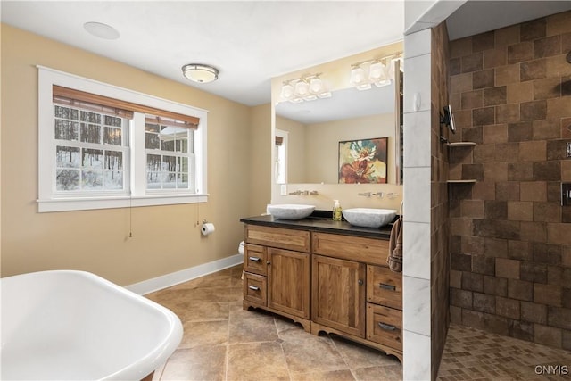 bathroom with double vanity, a freestanding bath, a tile shower, and a sink