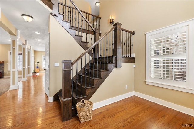 stairway with ornate columns, baseboards, wood finished floors, and recessed lighting