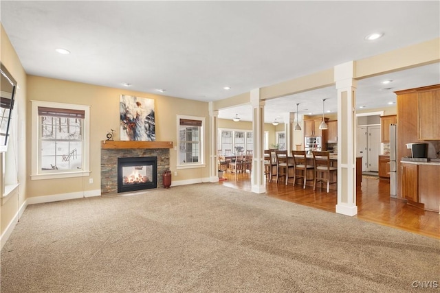 living area featuring ornate columns, recessed lighting, carpet flooring, and a multi sided fireplace