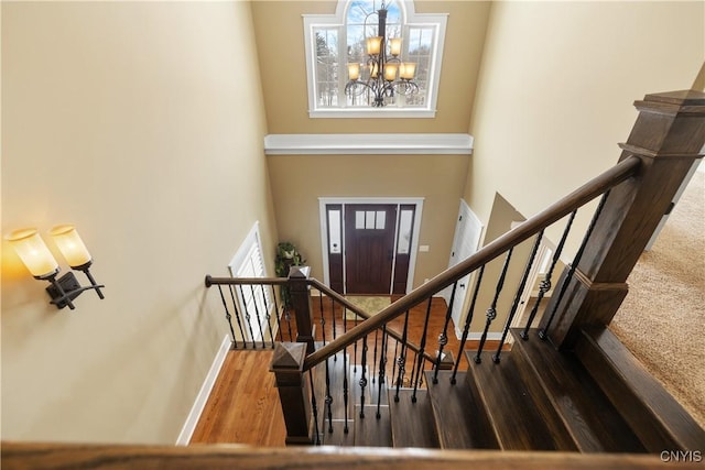 foyer with a chandelier, a high ceiling, wood finished floors, and baseboards