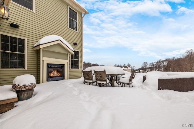 snow covered patio with a glass covered fireplace