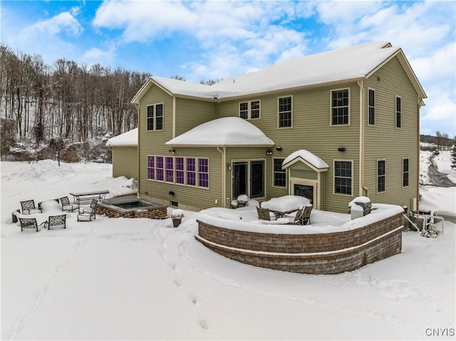 snow covered house with a garage and a fire pit