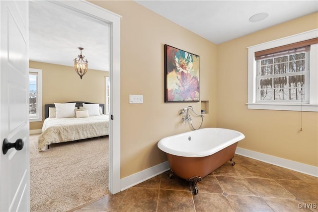 bathroom featuring a soaking tub, baseboards, and tile patterned floors