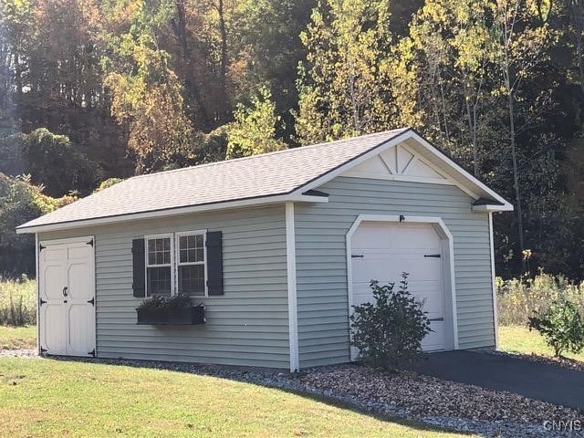 detached garage with aphalt driveway and a wooded view