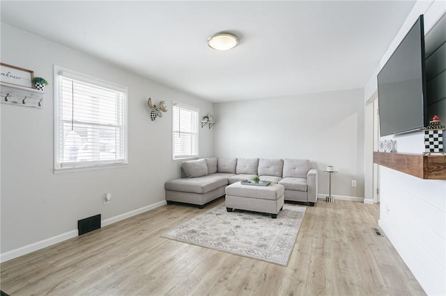 living area with visible vents, light wood-style flooring, and baseboards