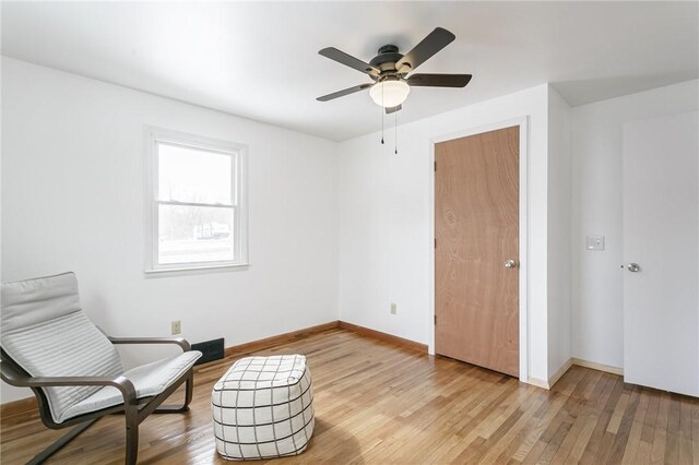 sitting room featuring light wood-style floors, baseboards, and a ceiling fan