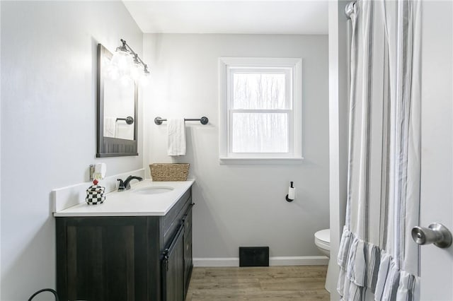 bathroom featuring vanity, wood finished floors, toilet, and baseboards