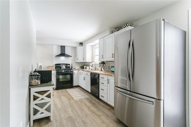 kitchen with light countertops, white cabinets, a sink, black appliances, and wall chimney exhaust hood