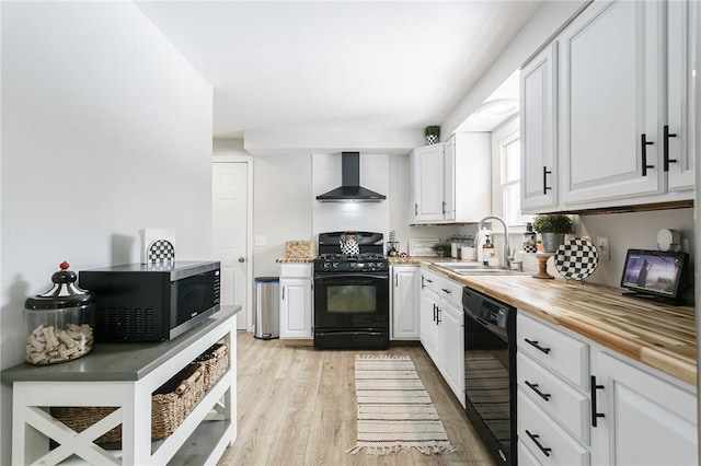 kitchen with light wood-style flooring, white cabinets, wall chimney range hood, and black appliances