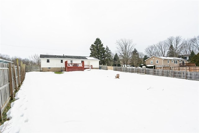 yard layered in snow featuring a fenced backyard and a wooden deck