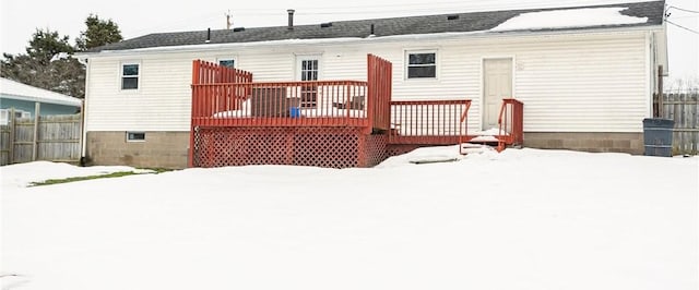 snow covered rear of property with fence and a wooden deck