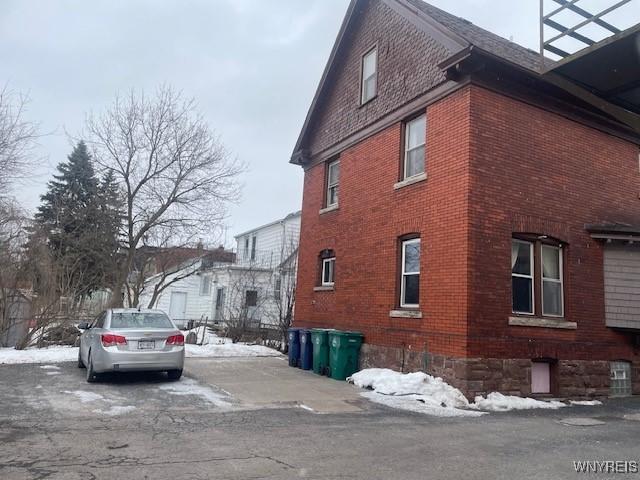 snow covered property with brick siding