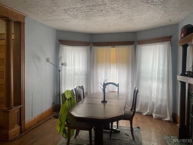 dining area featuring a healthy amount of sunlight, a textured ceiling, and wood finished floors